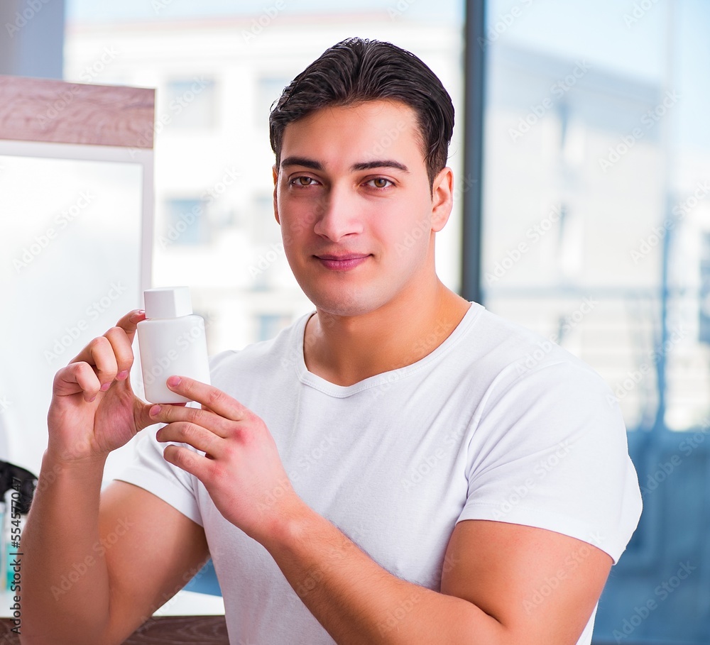 Young handsome man applying face cream Young handsome man applying face cream