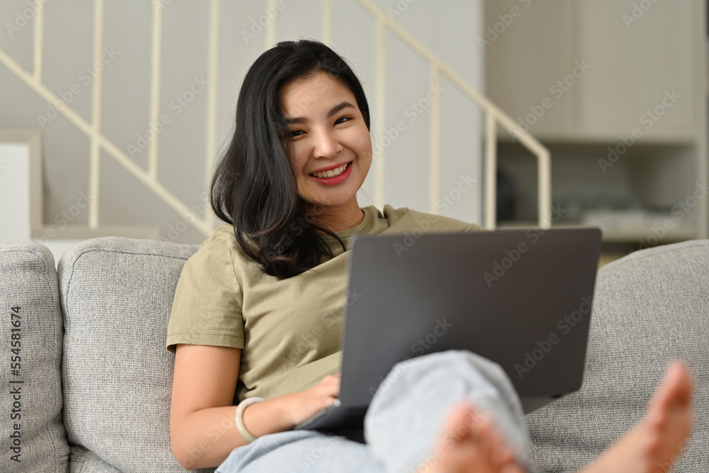 Smiling Young Asian woman using laptop, sitting on couch at home, Shopping online, Chatting in social network, Watching movie or freelancer working on computer. Smiling Young Asian woman using laptop, sitting on couch at home, Shopping online, Chatting in social network, Watching movie or freelancer working on computer.