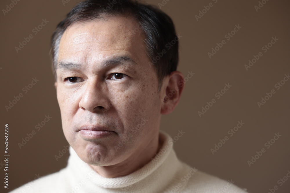 Middle-aged Asian man in white turtleneck wool sweater under gray background. Concept image of Warm Biz, stability in daily life, and sustainable living. Middle-aged Asian man in white turtleneck wool sweater under gray background. Concept image of Warm Biz, stability in daily life, and sustainable living.