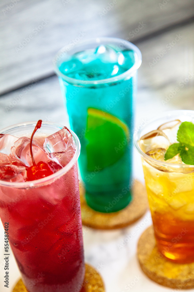 Three juicy lemonades of different colors in transparent plastic glasses with ice Three juicy lemonades of different colors in transparent plastic glasses with ice