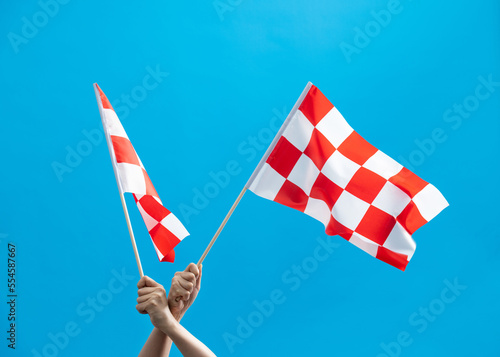 Human hands waving checkered flags on blue background