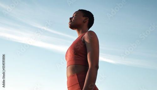 Fitness, meditation and woman on blue sky to breathe fresh air, freedom and energy to exercise, workout and do yoga or cardio training outdoor in nature. Black female take breath for mental health