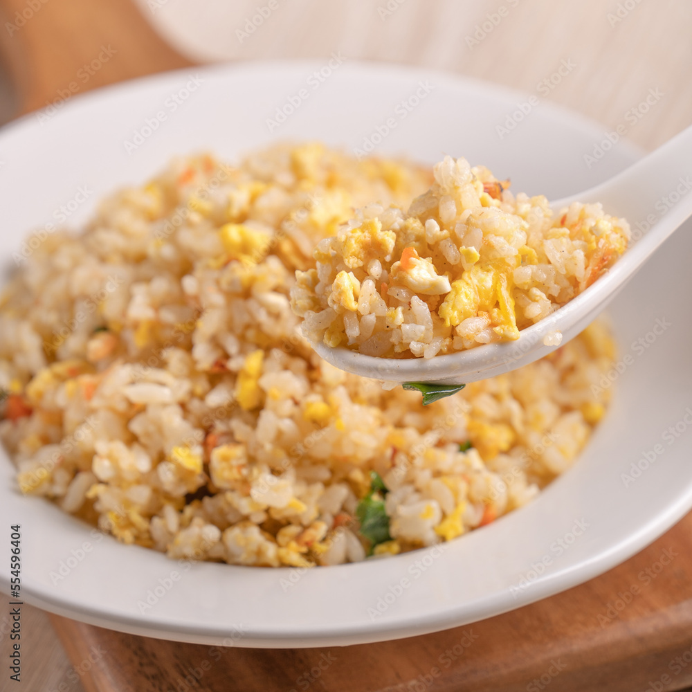 Eating Chinese fried rice in white plate on bright wooden table background. Eating Chinese fried rice in white plate on bright wooden table background.