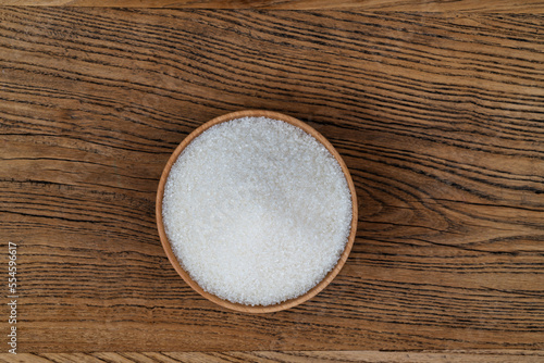 Granulated sugar in a bowl on wooden table