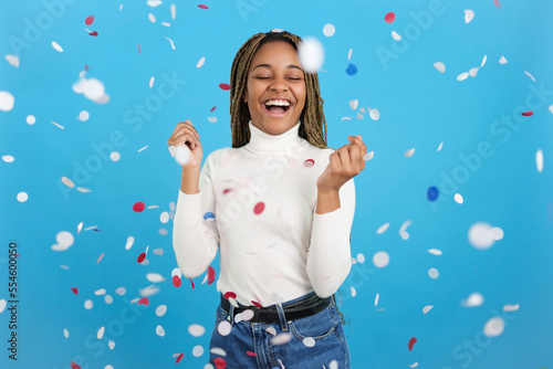 Excited African woman surrounded by flying confetti