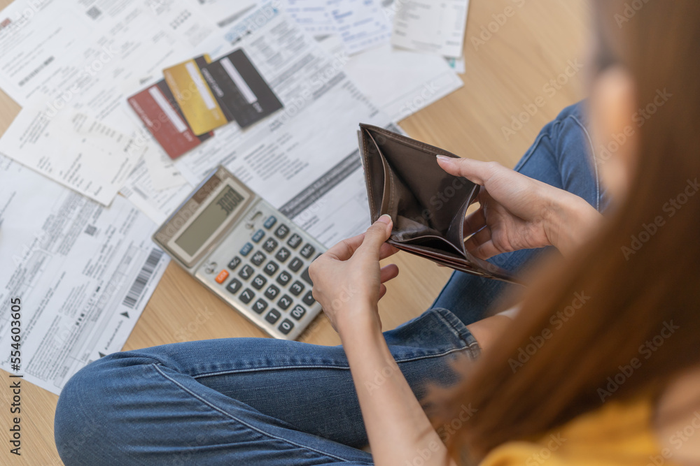 Obraz premium Stressed, problem people asian woman, girl sitting on floor at home, hand holding wallet open empty purse no money to pay bill, loan or expense in payment. Bankruptcy, bankrupt and debt financial.