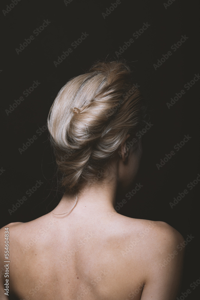 Natural beauty, make-up and fashion concept. Beautiful woman portrait with naked shoulders and hair bun. Model standing back to camera in black studio background with copy space. Soft filter applied Natural beauty, make-up and fashion concept. Beautiful woman portrait with naked shoulders and hair bun. Model standing back to camera in black studio background with copy space. Soft filter applied