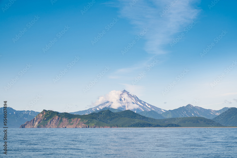 Summer landscape of the coastline with snow covered volcano. Kamchatka