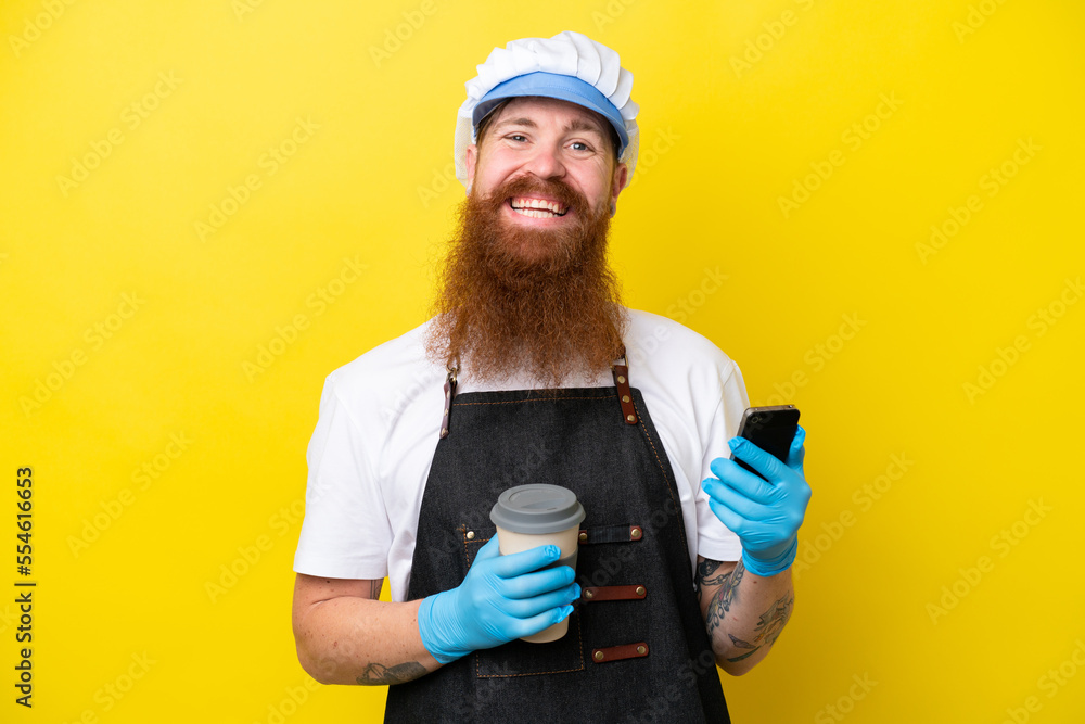 Fishmonger wearing an apron isolated on yellow background holding coffee to take away and a mobile Fishmonger wearing an apron isolated on yellow background holding coffee to take away and a mobile