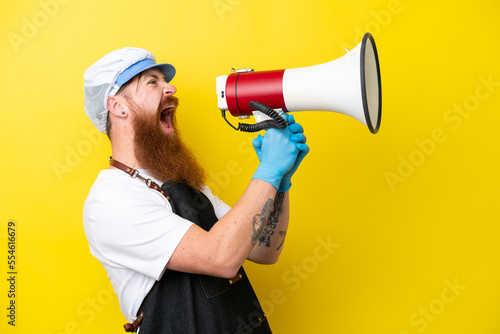 Foto Fishmonger wearing an apron isolated on yellow background shouting through a meg
