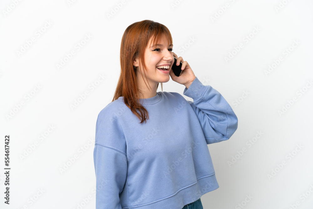 Redhead girl isolated on white background keeping a conversation with the mobile phone Redhead girl isolated on white background keeping a conversation with the mobile phone