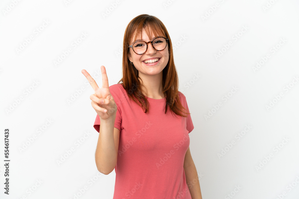 Redhead girl isolated on white background smiling and showing victory sign Redhead girl isolated on white background smiling and showing victory sign