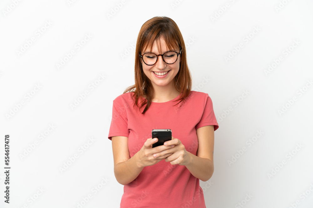 Redhead girl isolated on white background sending a message with the mobile Redhead girl isolated on white background sending a message with the mobile