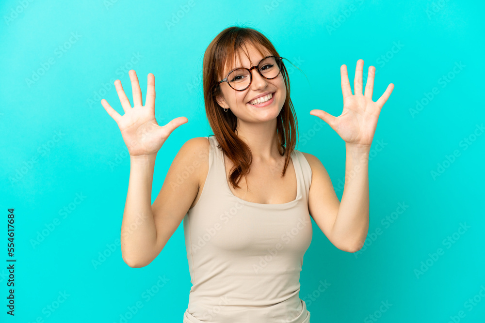 Redhead girl isolated on blue background counting ten with fingers Redhead girl isolated on blue background counting ten with fingers