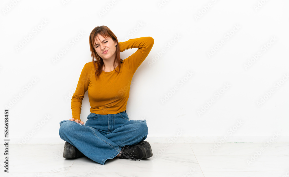 Redhead girl sitting on the floor isolated on white background with neckache Redhead girl sitting on the floor isolated on white background with neckache