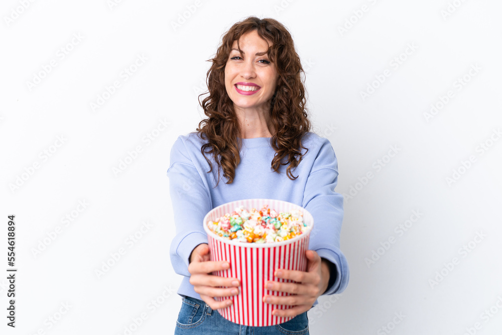 Young woman with curly hair isolated on white background holding a big bucket of popcorns Young woman with curly hair isolated on white background holding a big bucket of popcorns