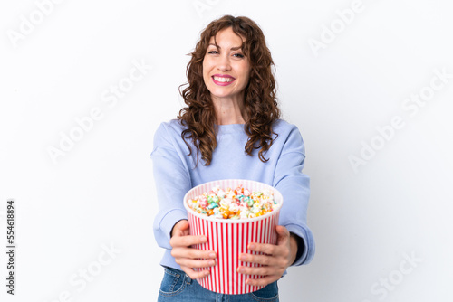 Young woman with curly hair isolated on white background holding a big bucket of popcorns