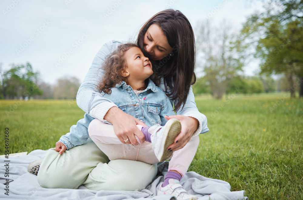 Love, mother and girl on blanket at park, having fun and bonding. Care, family and happy mom embrace with .daughter at garden, smiling and enjoying quality time together outdoors in nature on grass.