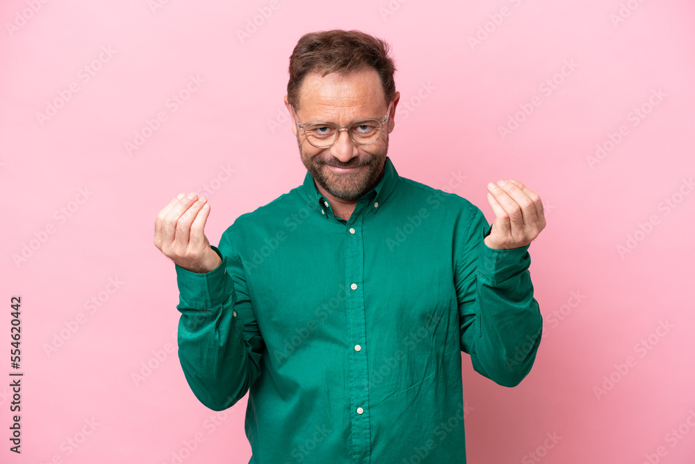 Middle age caucasian man isolated on pink background making money gesture Middle age caucasian man isolated on pink background making money gesture