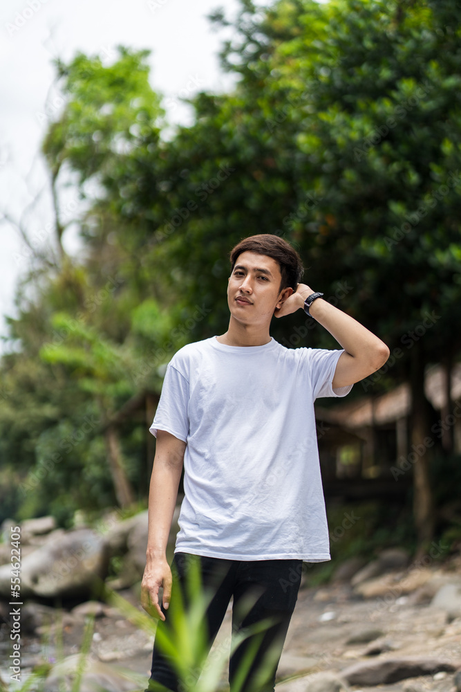 An Asian Man With White Shirt Posing Near a River in the Nature An Asian Man With White Shirt Posing Near a River in the Nature