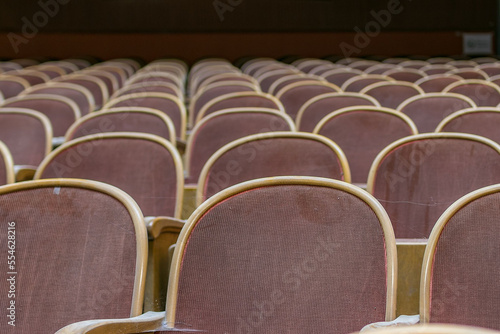 A close up of red wooden cinema seats, covered with red fabric, in old historical cinema.