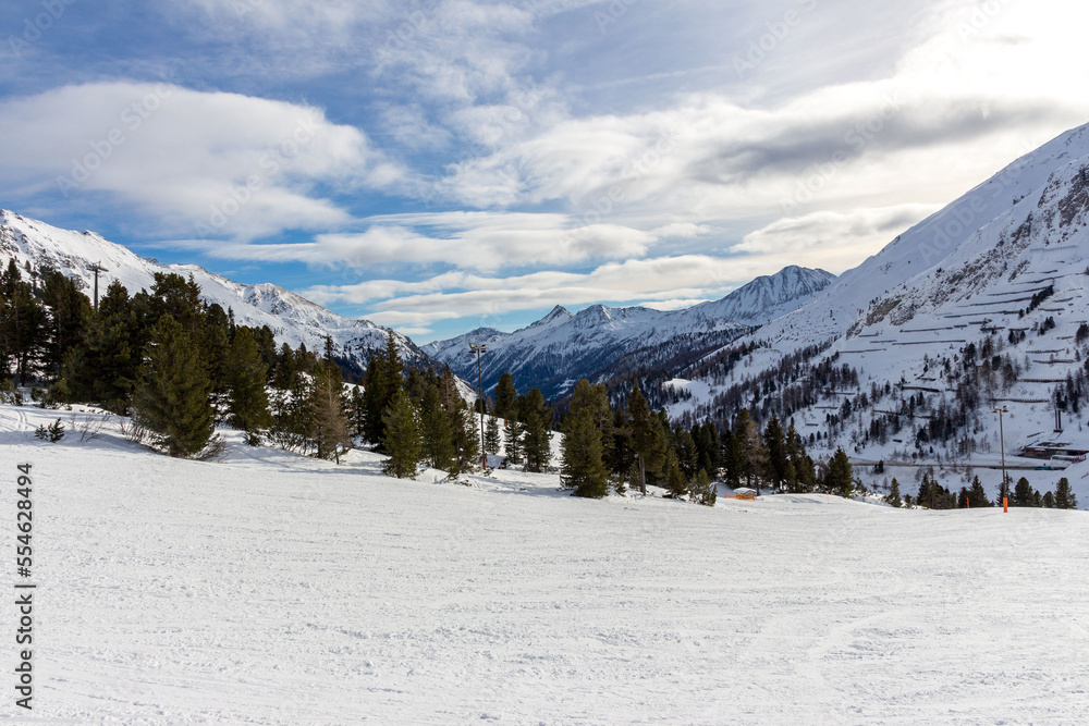 Beautiful winter landscape in the mountains, with a ski slope in the foreground. blue sky with clouds.