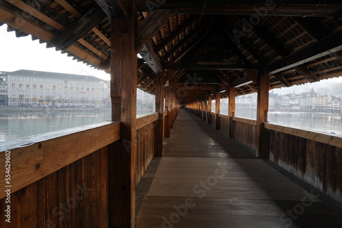 Chapel bridge over river Reuss. Interior of a roofed bridge in diminishing perspective. The other bank of the river is on the background with waterfront. © Lucia