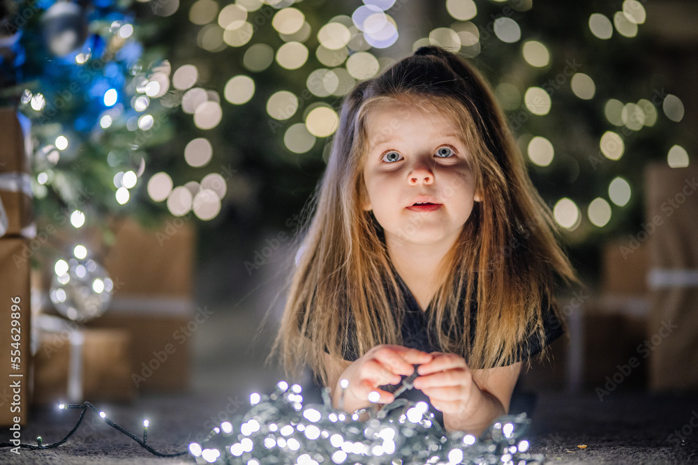 4 years old little girl laying down and looking up near Christmas