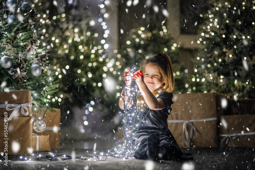 A little girl is playing with Christmas lights