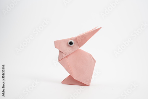 single pink paper origami hare rabbit with googly eyes isolated on a white background