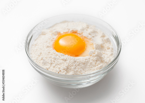 Bowl plate with flour and egg yolk on white background.