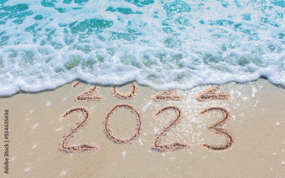 Message Year 2022 replaced by 2023 written on beach sand background. Good bye 2022 hello to 2023 happy New Year coming concept. - obrazy, fototapety, plakaty 