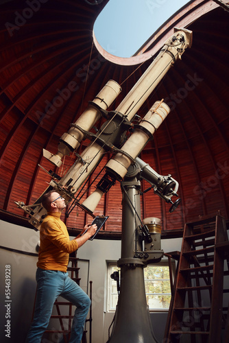 Photographie Astronomer with a big astronomical telescope in observatory doing science research