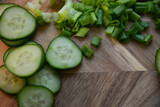 green fresh sliced onions with green sliced cucumber on a wooden board