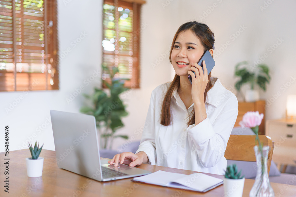 Working at home concept, Women talking on smartphone and working on laptop at modern home office Working at home concept, Women talking on smartphone and working on laptop at modern home office