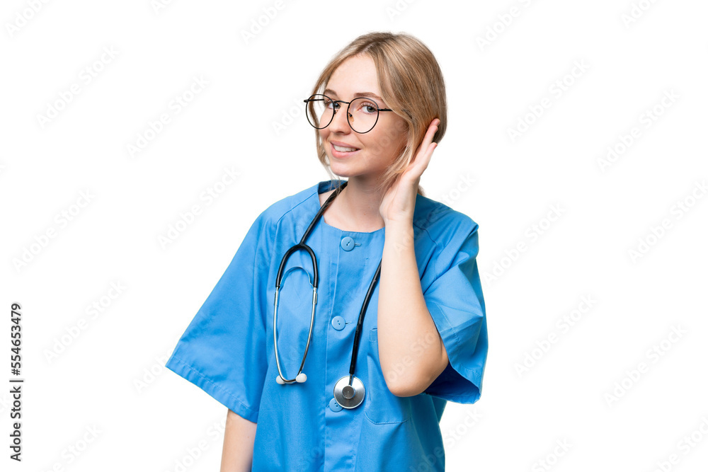 Young nurse English woman over isolated background listening to something by putting hand on the ear