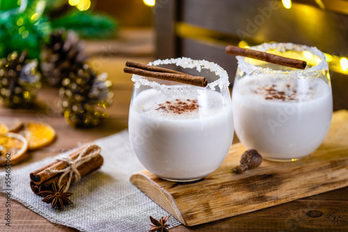 Christmas drink from raw eggs egg-nog on a wooden surface with a bokeh of rustic garlands photo