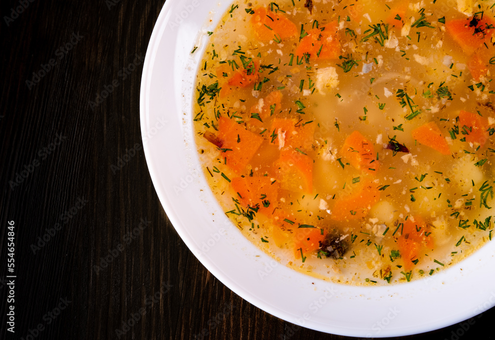 Fresh fish soup in white plate on black wooden table background Fresh fish soup in white plate on black wooden table background