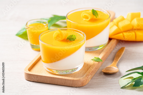 Delicious double colored mango panna cotta mousse pudding on wooden table background. photo