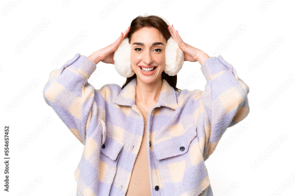 Young caucasian woman wearing winter muffs over isolated chroma key background with surprise expression Young caucasian woman wearing winter muffs over isolated chroma key background with surprise expression