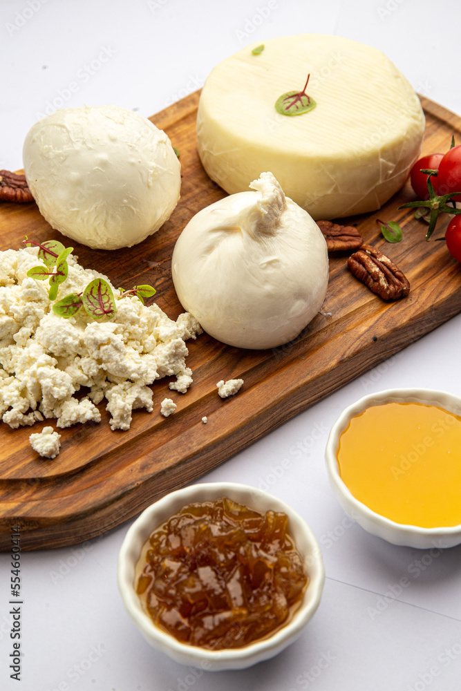 Assorted cheeses on a board with honey and jam Assorted cheeses on a board with honey and jam
