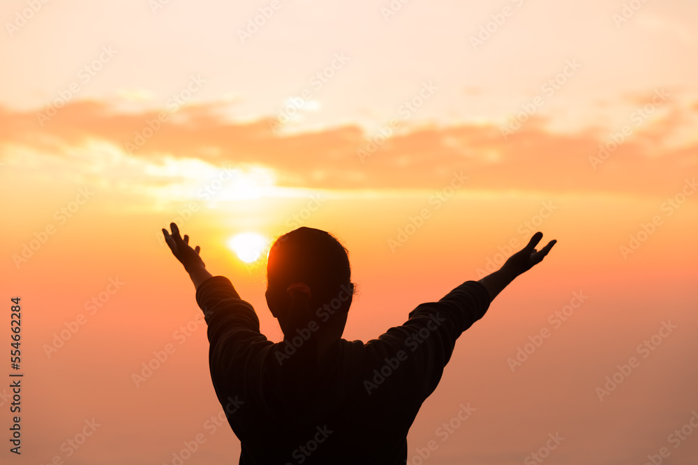 Concept Christian person worship or pray to God. Christian woman silhouette with love, faith, devotion to God with sunrise sky background. worship God for peace, victory, success with hope. religion