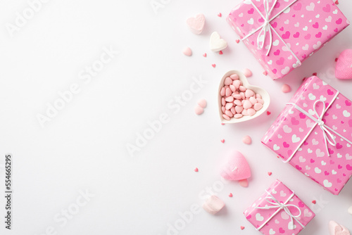 Valentine's Day concept. Top view photo of pink gift boxes heart shaped saucer with sprinkles marshmallow and candles on isolated white background with copyspace