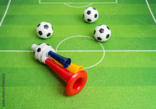 Football soccer triple fan trumpet with toy football on green grass