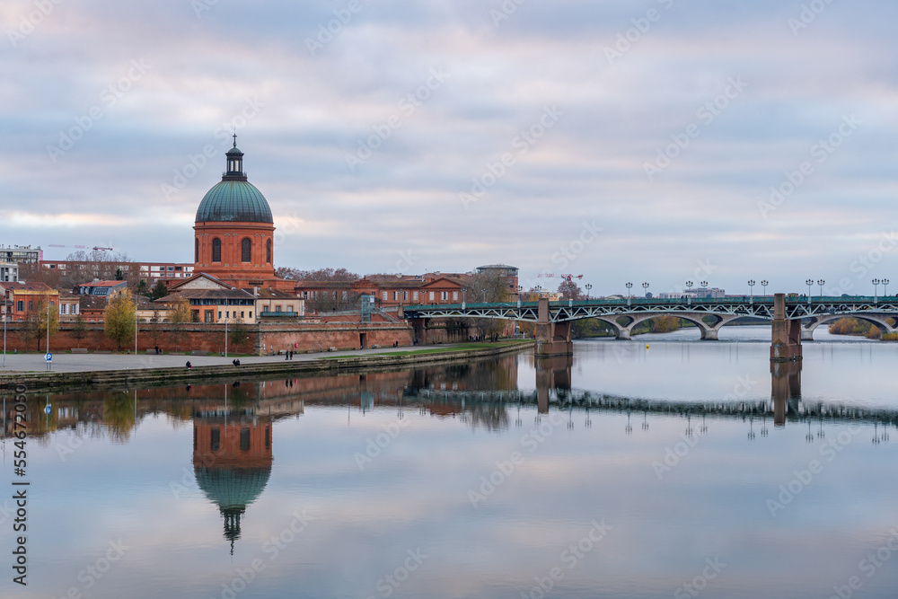 Scenic cityscape view on the dome of St Joseph de la Grave chapel and St Peter bridge with reflection in Garonne river, Toulouse, France