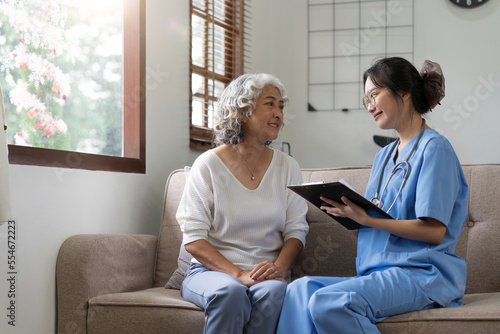 Asian senior woman patient on sofa with medical doctor woman wearing stethoscope diagnosis