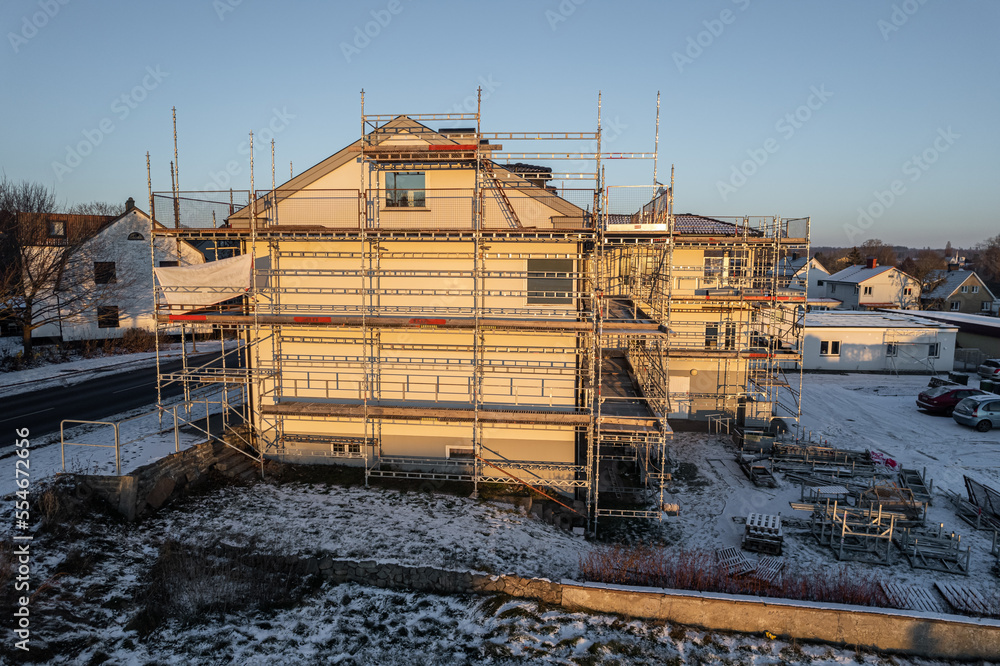 Fototapeta premium Reconstruction of residential building in European village, working scaffold, aerial view