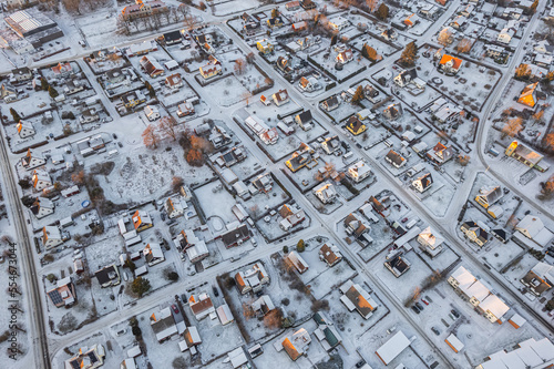 Aerial view on little European village in Sweden in winter, many private houses. Snowy weather, sunset. Warm sunlight. 