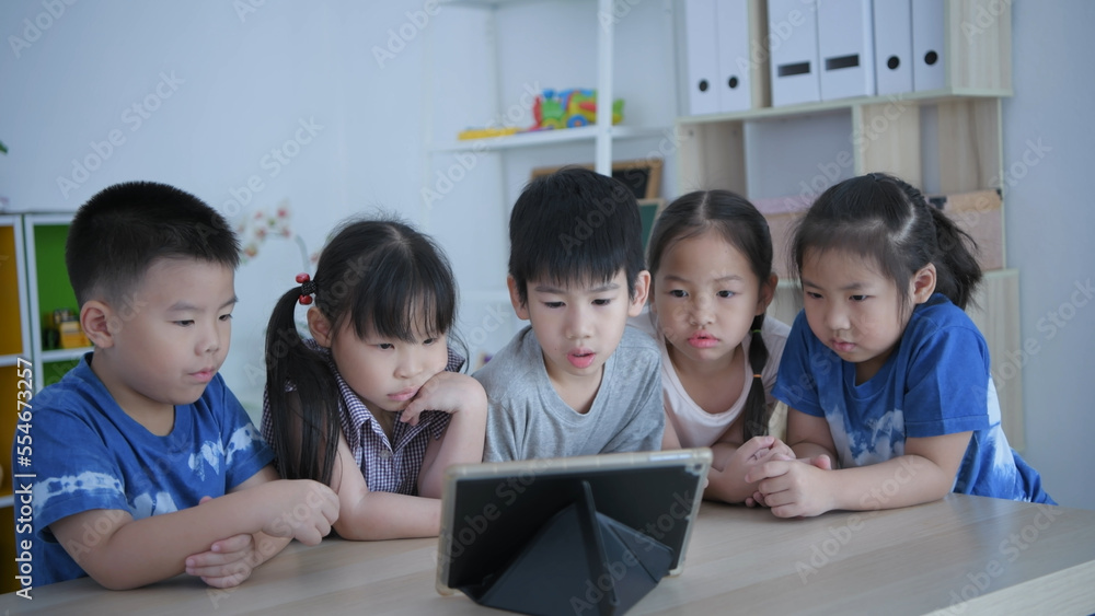 Educational concept of 4k Resolution. kindergarten teacher teaching children using tablet in classroom. Educational concept of 4k Resolution. kindergarten teacher teaching children using tablet in classroom.