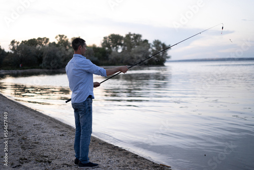 Man fishing in the evening on the lake. Peaceful summer fishing in nature